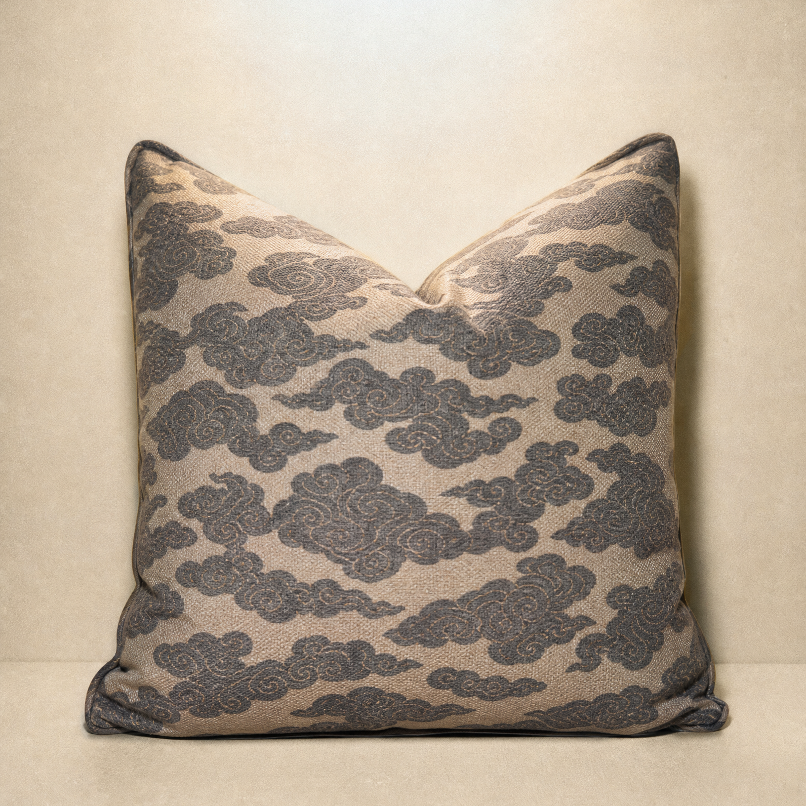 A square decorative throw pillow with a beige background and a dark gray cloud pattern, set against a matching beige backdrop.